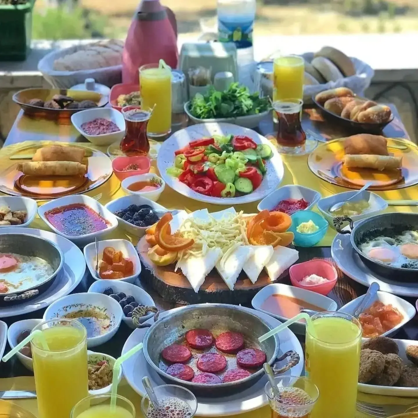 A Turkish breakfast spread from above: cheeses, olives, jams, fried eggs and orange juice