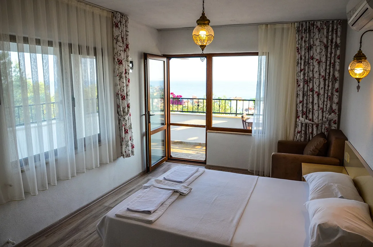 Balkon kapısı açık oda; balkondan Edremit Körfezi görünüyor