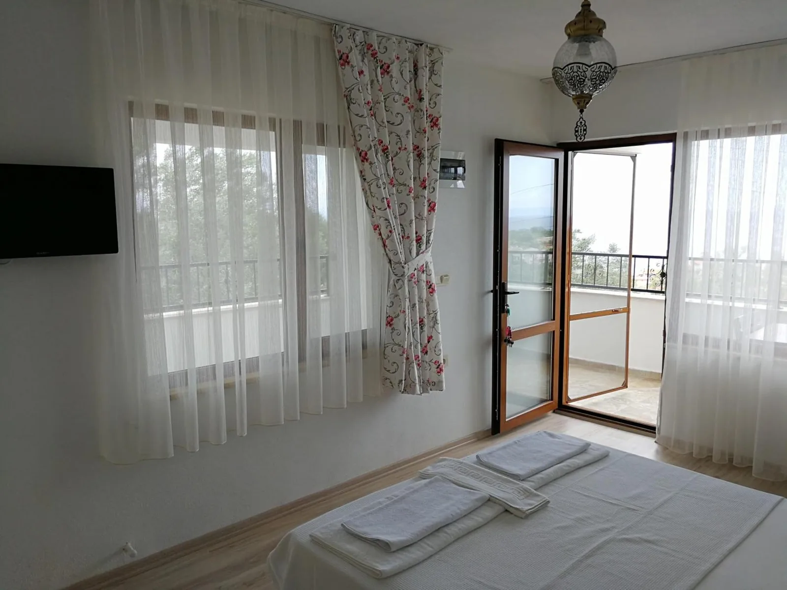 Üç kişilik oda: televizyon, balkon kapısı ve iki yatak