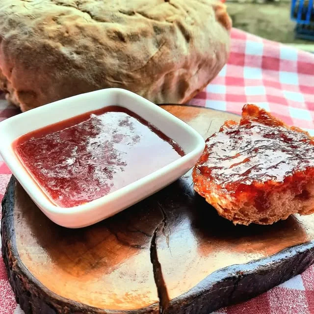 Ahşap kütükte kâsede vişne reçeli ve üzerine sürülmüş taze ekmek
